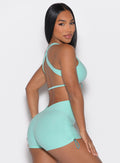 right side profile view of a model looking over her shoulder wearing the Toggluxe bra in Oasis color paired with the matching shorts 
