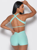 back profile view of a model facing to the right side wearing the Toggluxe bra in Oasis color