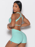 back left side profile view of a model looking over her shoulder wearing the Toggluxe bra in Oasis color
