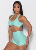 front left side profile view of a model with both hands resting on her thighs wearing the Toggluxe bra in Oasis color