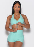 front profile view of a model adjusting the front toggle on the bra wearing the Toggluxe bra in Oasis color