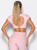 back profile view of a model with both hands on her thighs wearing the Toggluxe Tee in Candy color