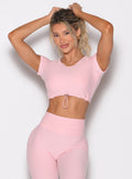 front profile view of a model holding her hair with both hands wearing the Toggluxe Tee in Candy color