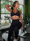 Model sitting on a exercise bicycle wearing our Toggluxe Bra in black color paired with the matching leggings