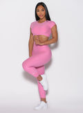 front profile view of a model balancing herself with one leg wearing the Toggle Pull Leggings in Bubblegum color
