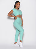front right side profile view of a model with one hand on her waist wearing the Toggle Pull Leggings in Oasis color