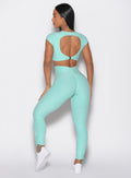 back profile view of a model facing to the left wearing the Toggle Pull Leggings in Oasis color