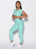 front left side profile view of a model with both hands on the waistband wearing the Toggle Pull Leggings in Oasis color