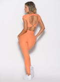 back profile view of a model facing to the left wearing the Toggle Pull Leggings in Tangerelle color