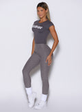 front left side profile view of a model wearing the Bombshell Era Tee in solid champion gray color with the matching leggings 