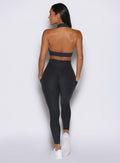 back profile view of a model facing to the left wearing the Toned 7/8 Leggings in Charcoal color