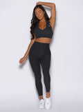 front view of a model with one hand resting on top of her head wearing the Toned 7/8 Leggings in Charcoal color