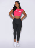 front view of a model with both hands behind wearing the Toned 7/8 Leggings in Charcoal color