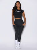 front view of a model wearing the Bombshell Era Tee in black color  paired with the matching leggings 