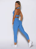 left side profile view of a model looking over her shoulder wearing the Toned 7/8 Leggings in Legacy Blue color