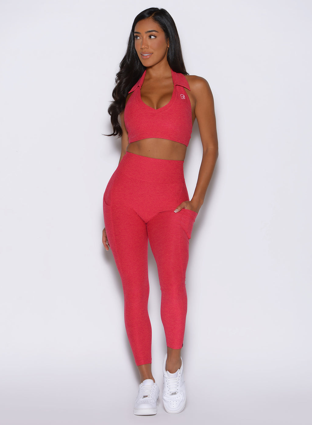 model captured from the front looking to the right side with one hand in the side pocket wearing the Toned 7/8 Leggings in Victory ruby color