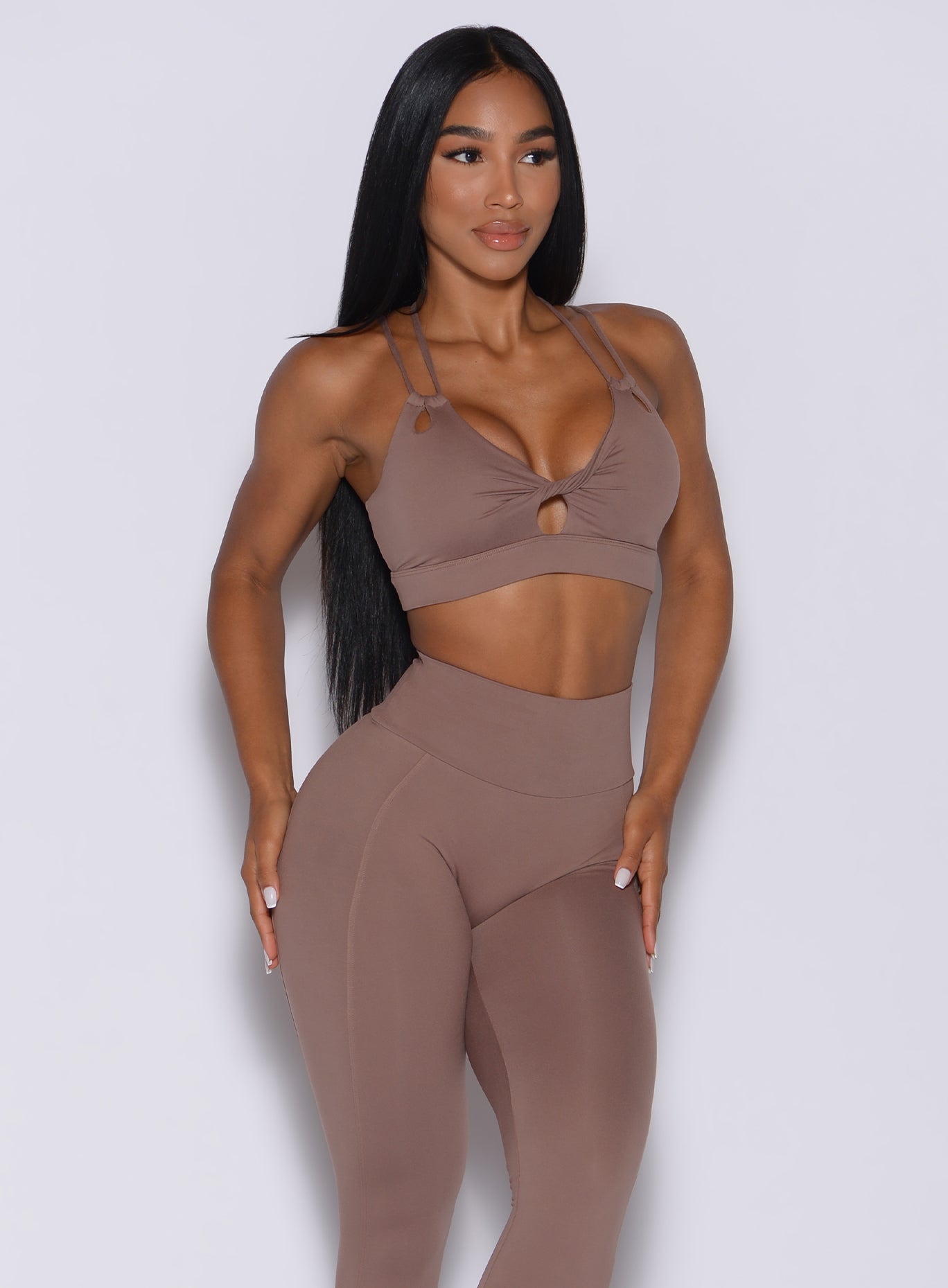 front profile view of a model in our twist sports bra in tan color and a matching leggings
