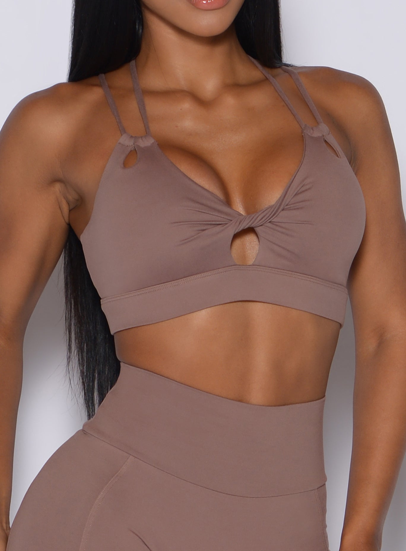 Zoomed in front profile view of a model wearing our twist sports bra in tan color 