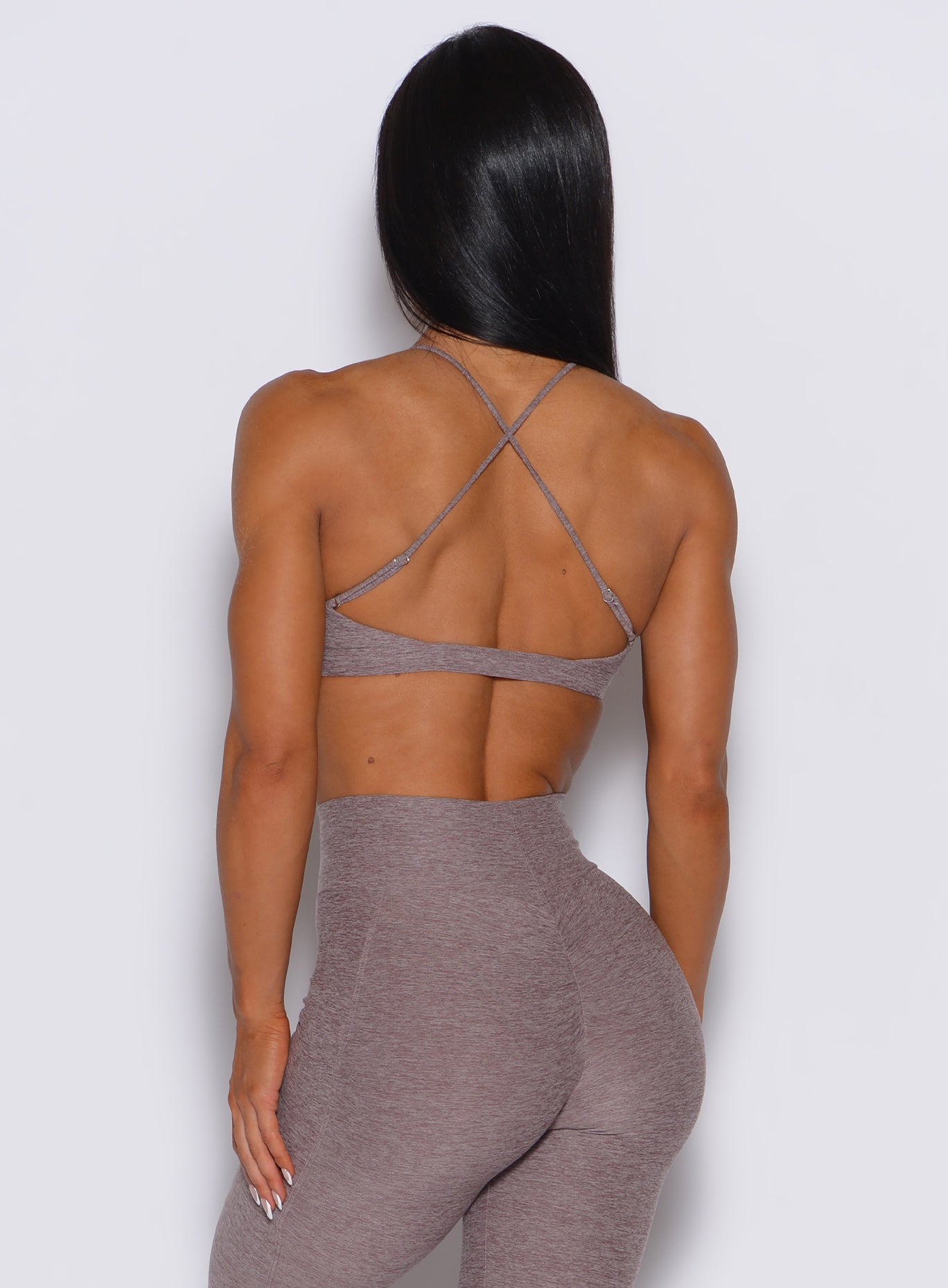 back profile picture of a model wearing our Tiny Twist bra in London Fog color along with the matching leggings.