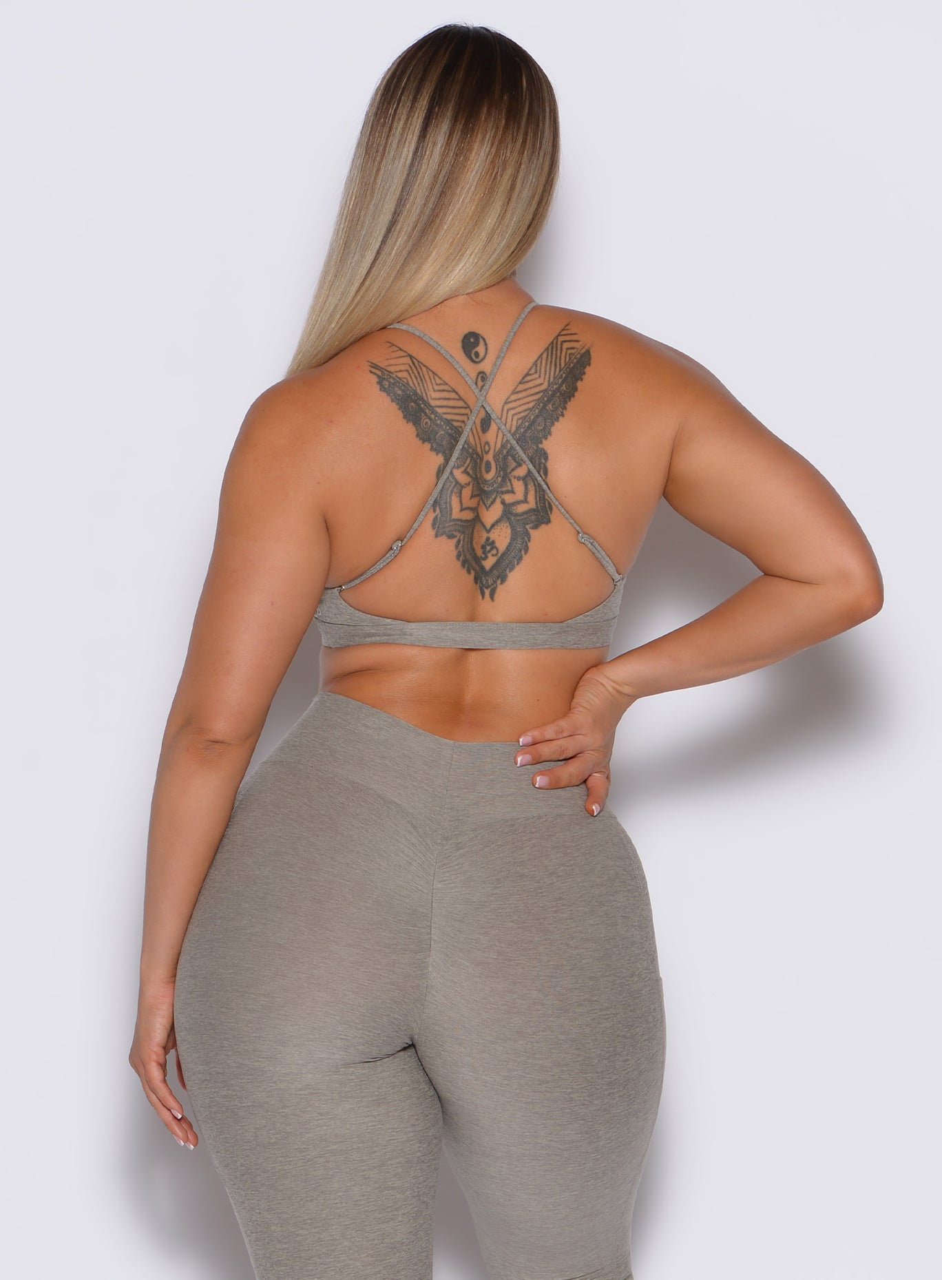 A back-profile picture of a model wearing our Twist sports bra in Nori color, along with the matching leggings.