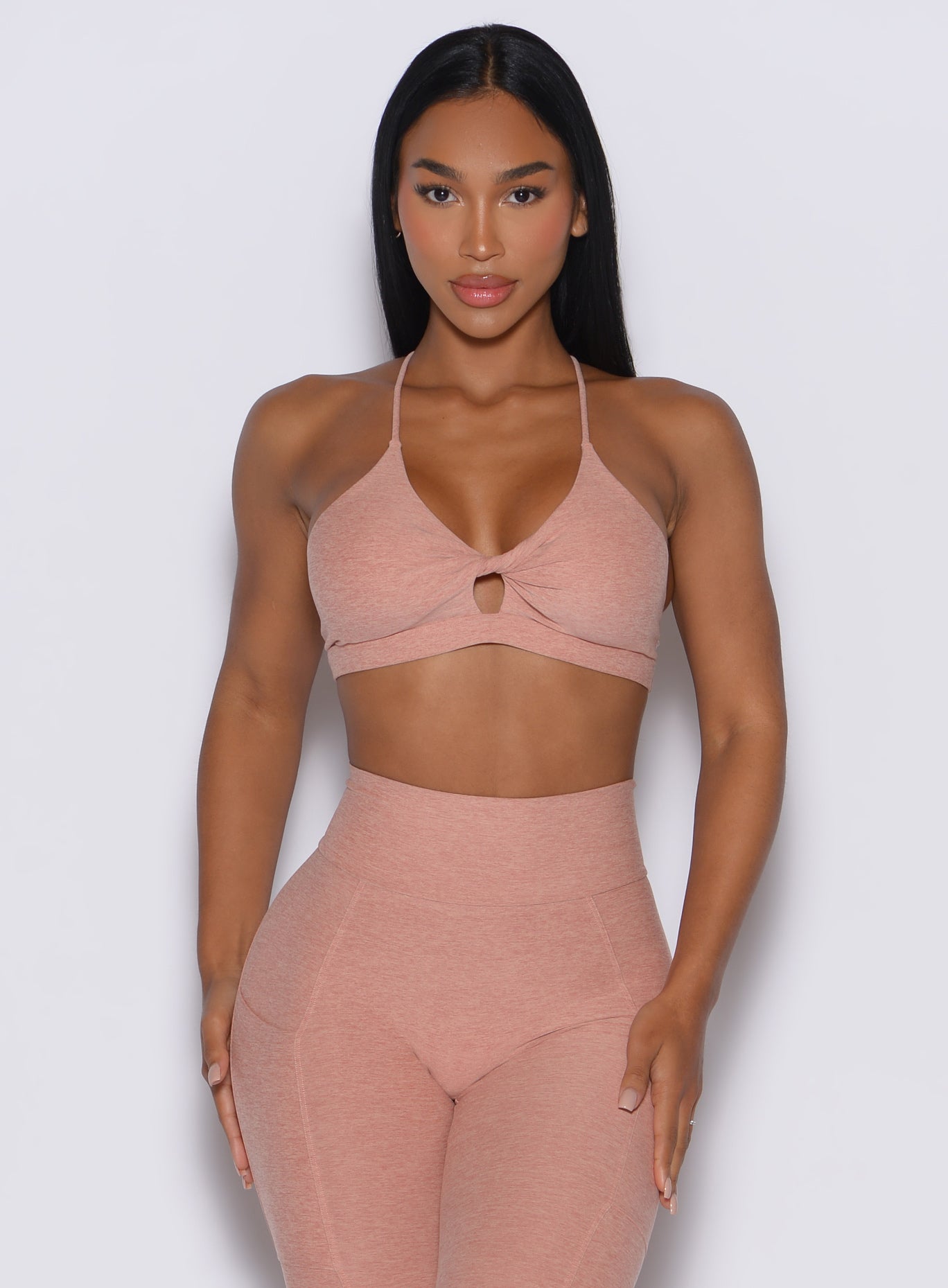 front profile view of a model wearing our tiny twist bra in nude sand color along with the matching leggings 
