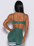 Back profile picture of a model wearing our twist mini bra in emerald green color along with a matching thigh high leggings
