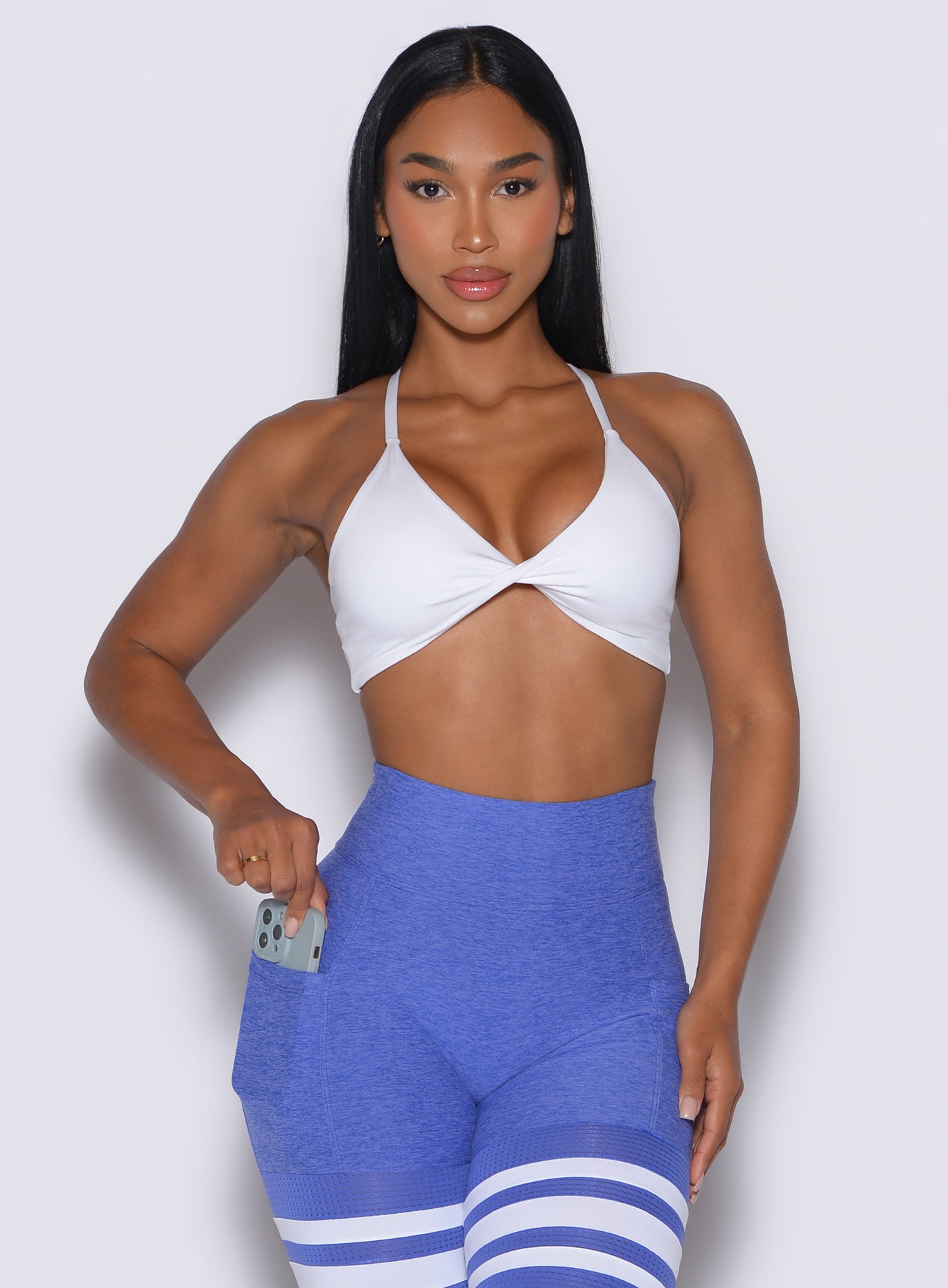 Front profile view of a model wearing our white twist mini bra along with a matching thigh high leggings 