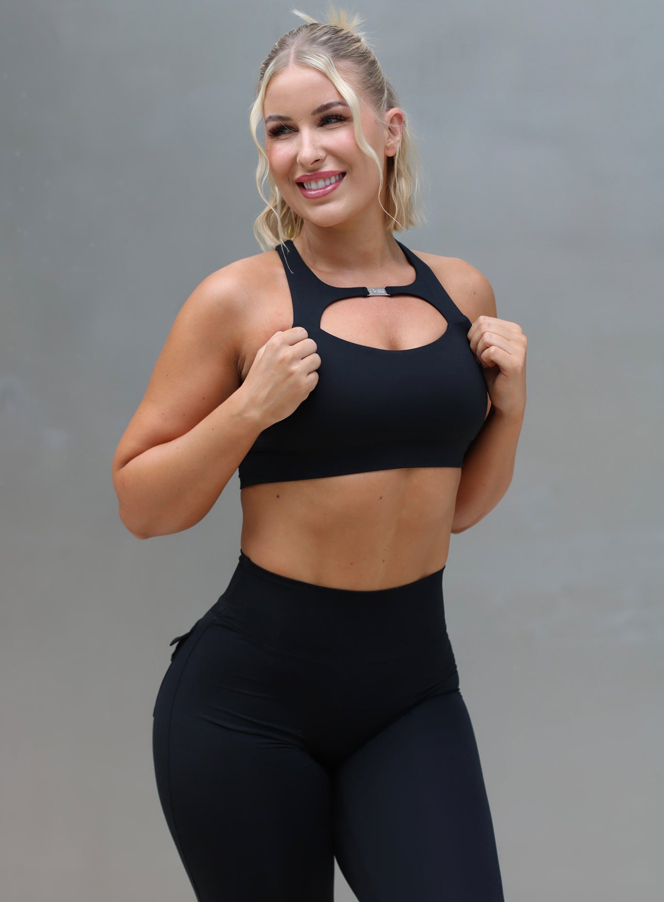 Front profile picture of a model wearing our black two way bra along with the matching high waist leggings