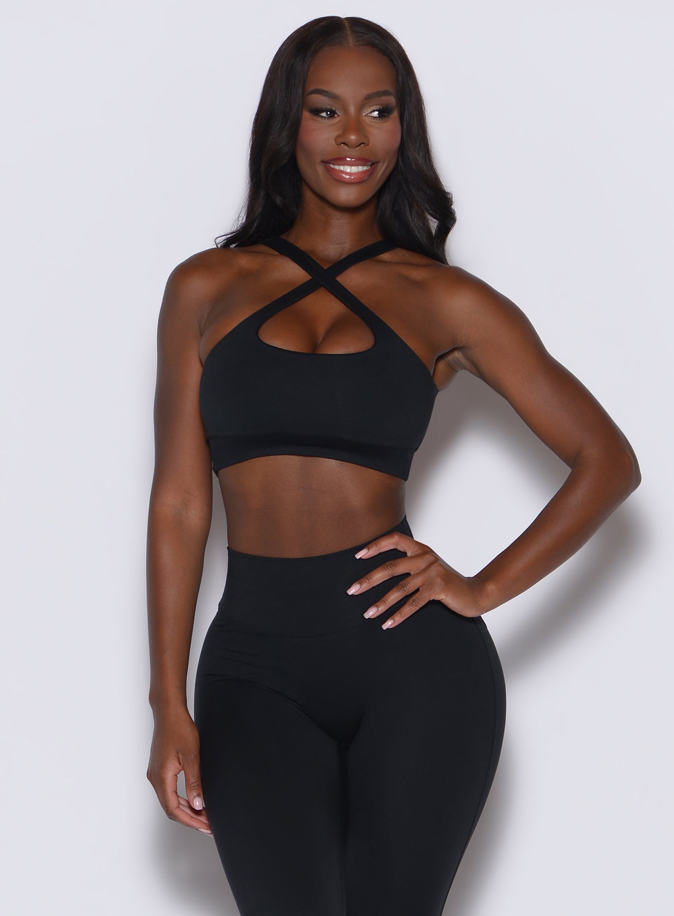 Front profile view of a model wearing our black two way bra along with the matching leggings 