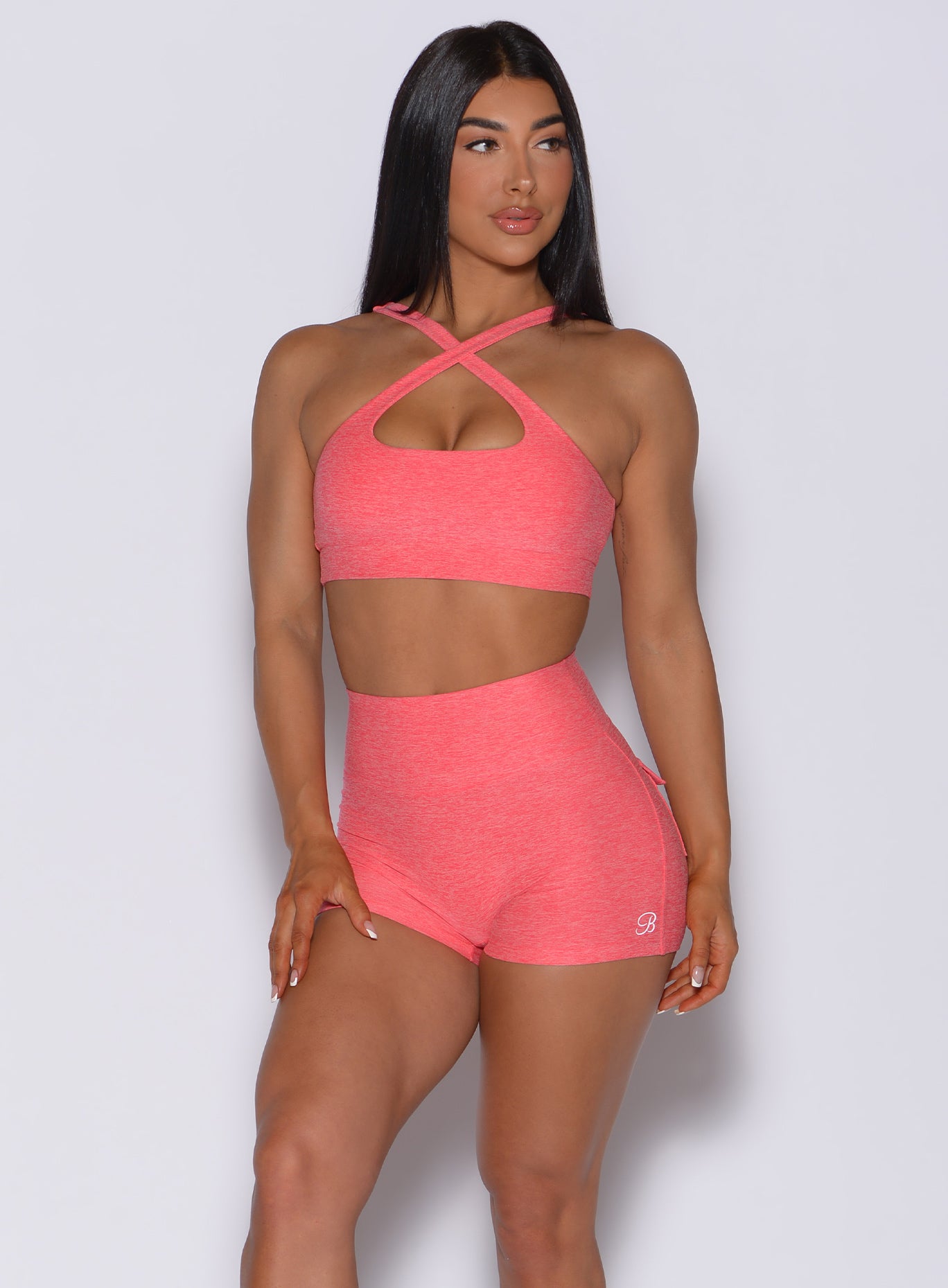 front profile view of a model in our two way sports bra in papaya color and a matching high waisted shorts 