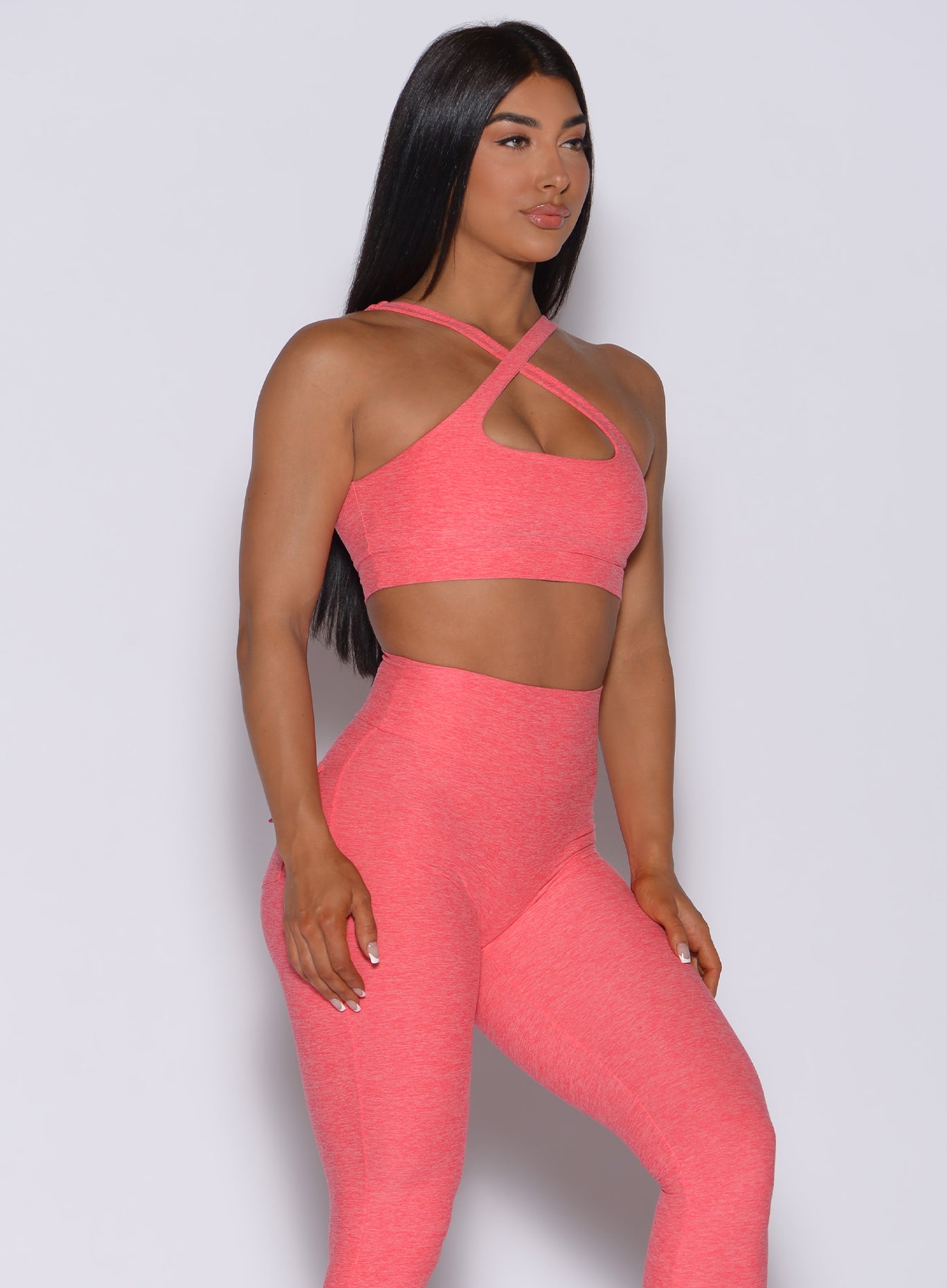 Front profile view of a model in our two way bra and high waisted  leggings in papaya colior