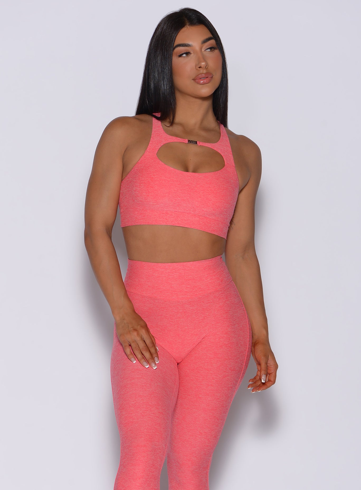 front profile view of a model in our two way bra in papaya color and a matching leggings