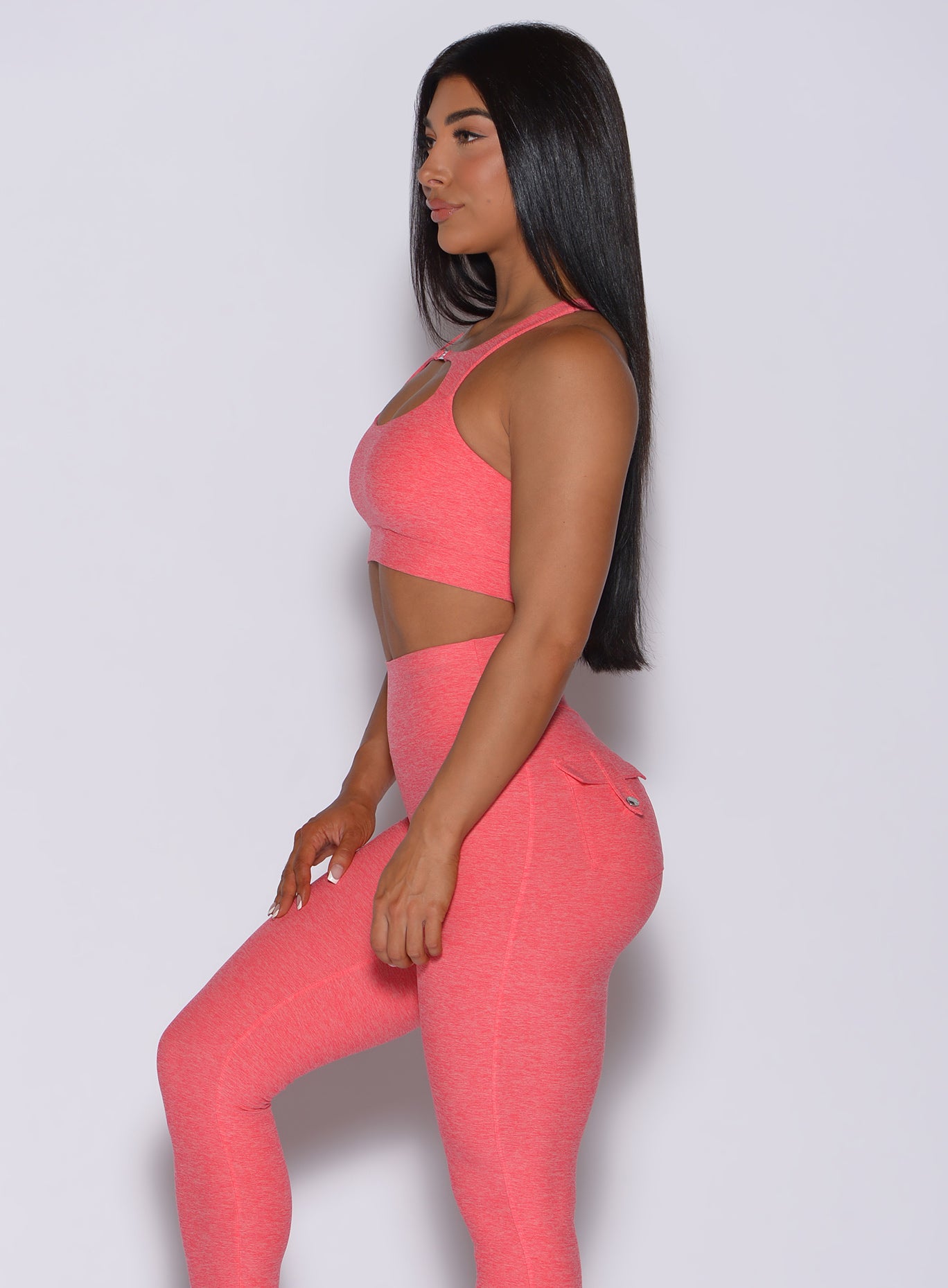 Left side profile view of a model in our two way bra in papaya color and a matching leggings
