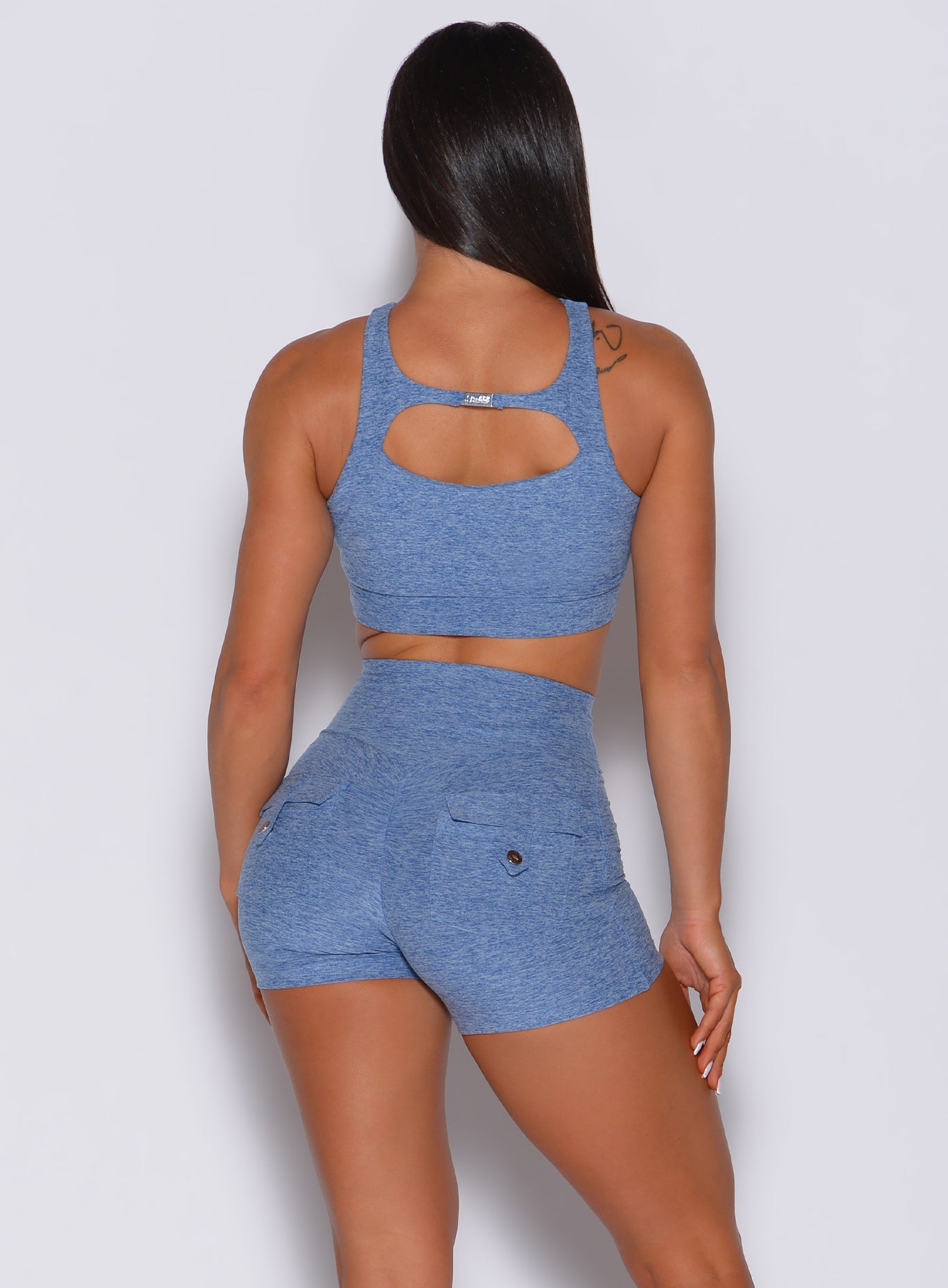 Back profile view of a model wearing our two way sports bra in sky blue color and a matching high waisted shorts