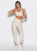 front profile view of a model wearing the Uplift peach leggings in pearl white color paired with the matching tank bra