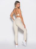 back right side profile view of a model looking over her shoulder wearing the Uplift peach leggings in pearl white color