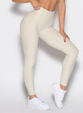 close up front right side profile view of a model wearing the Uplift peach leggings in pearl white color