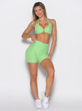 front profile view of a model wearing the Uplift Peach Shorts in Electric Green color paired with the matching bra 