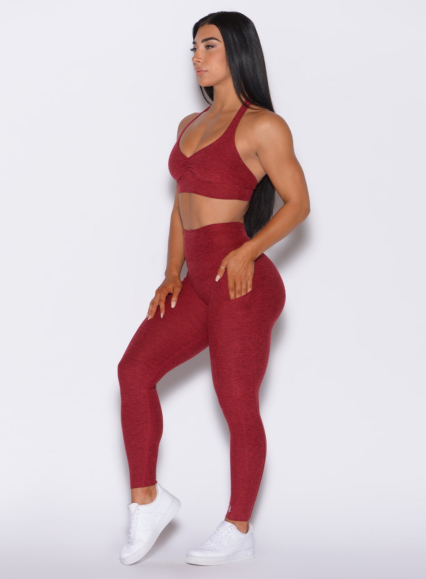 Left side profile view of a model angled left wearing our V Back Leggings in garnet red along with the matching bra