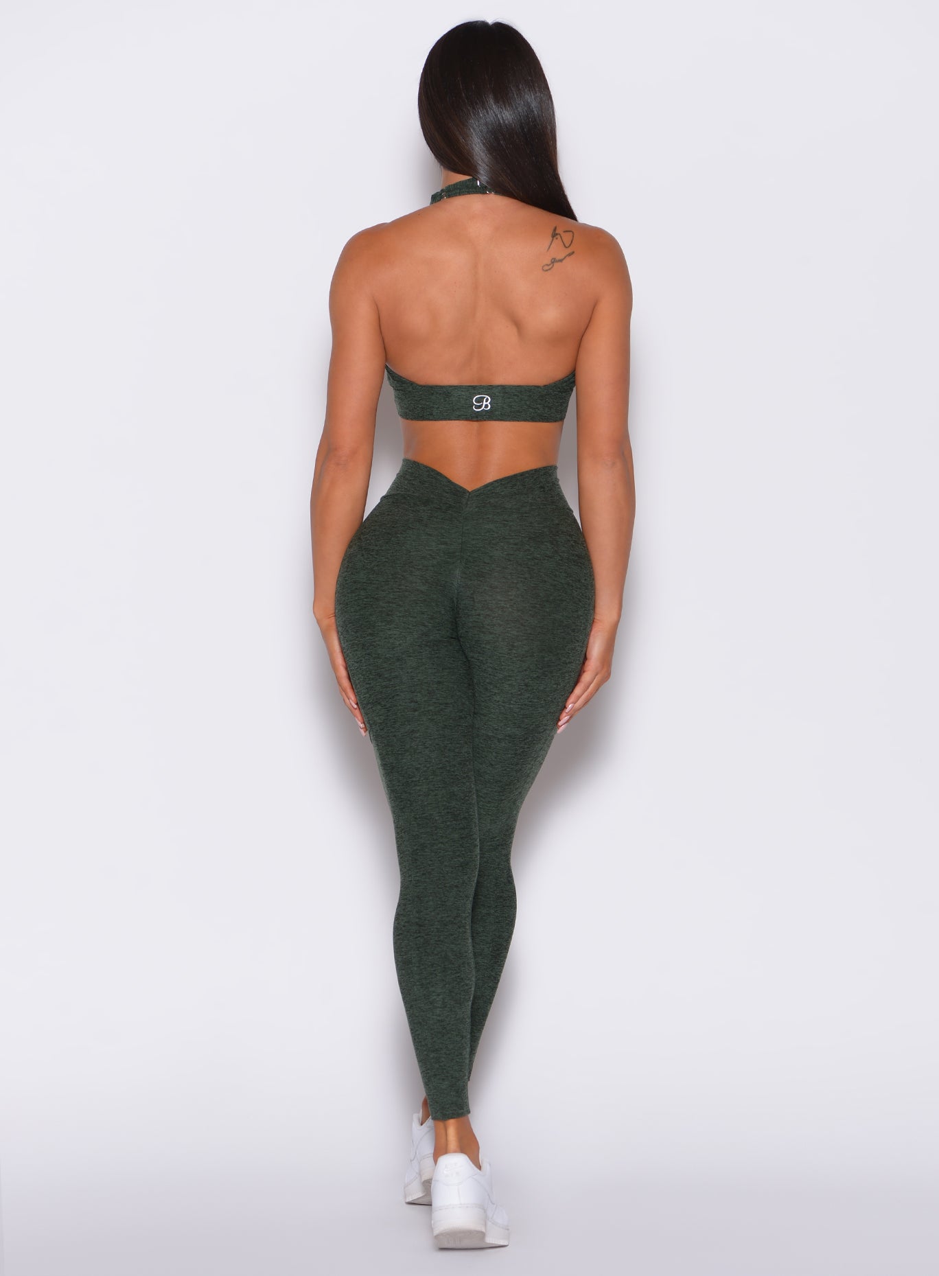 Back profile view of a model in our V Back Leggings in hunter green color along with the matching bra