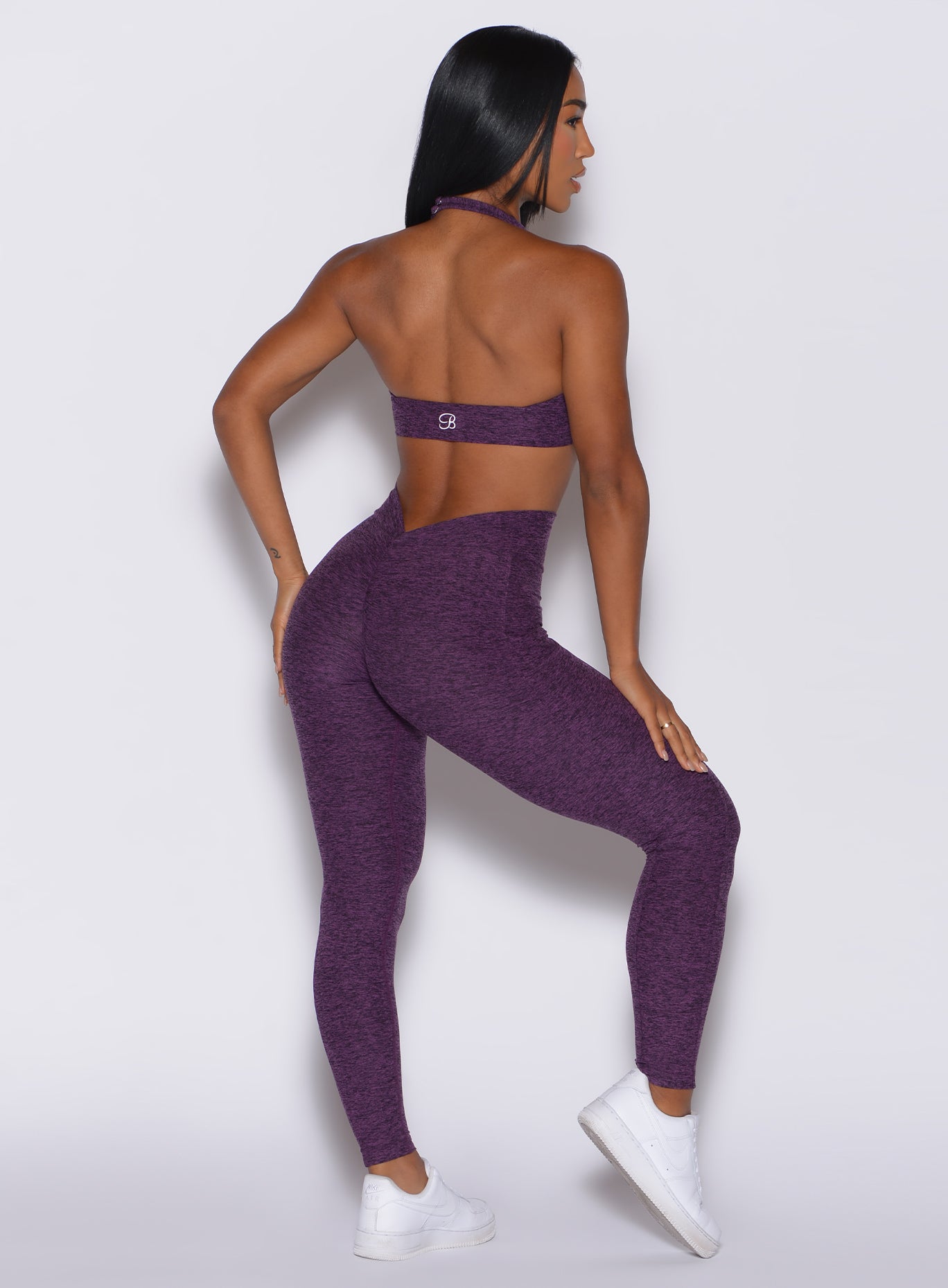 Back profile view of a model facing to her right wearing our V Back Leggings in purple passion color along with the matching bra