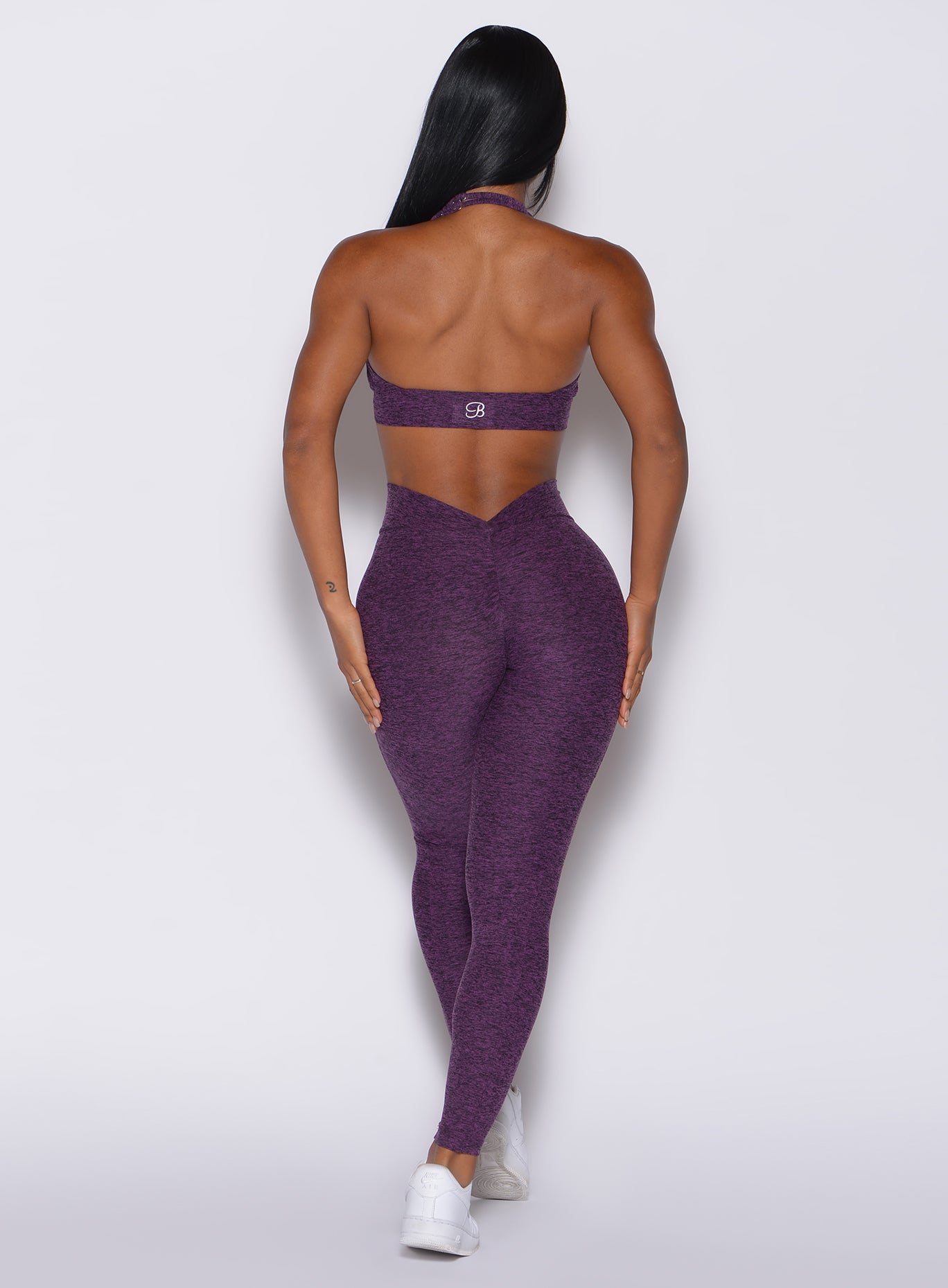 back profile view of a model wearing our V Back Leggings in purple passion color along with the matching bra