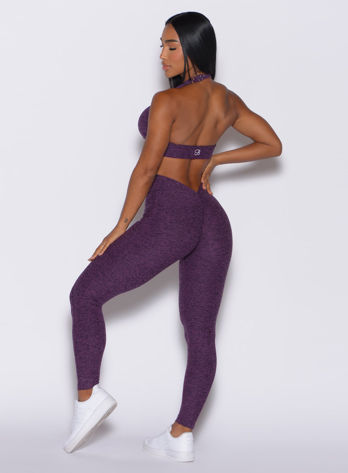 Left side profile view of a model angled slightly to her right wearing our V Back Leggings in purple passion color along with the matching bra