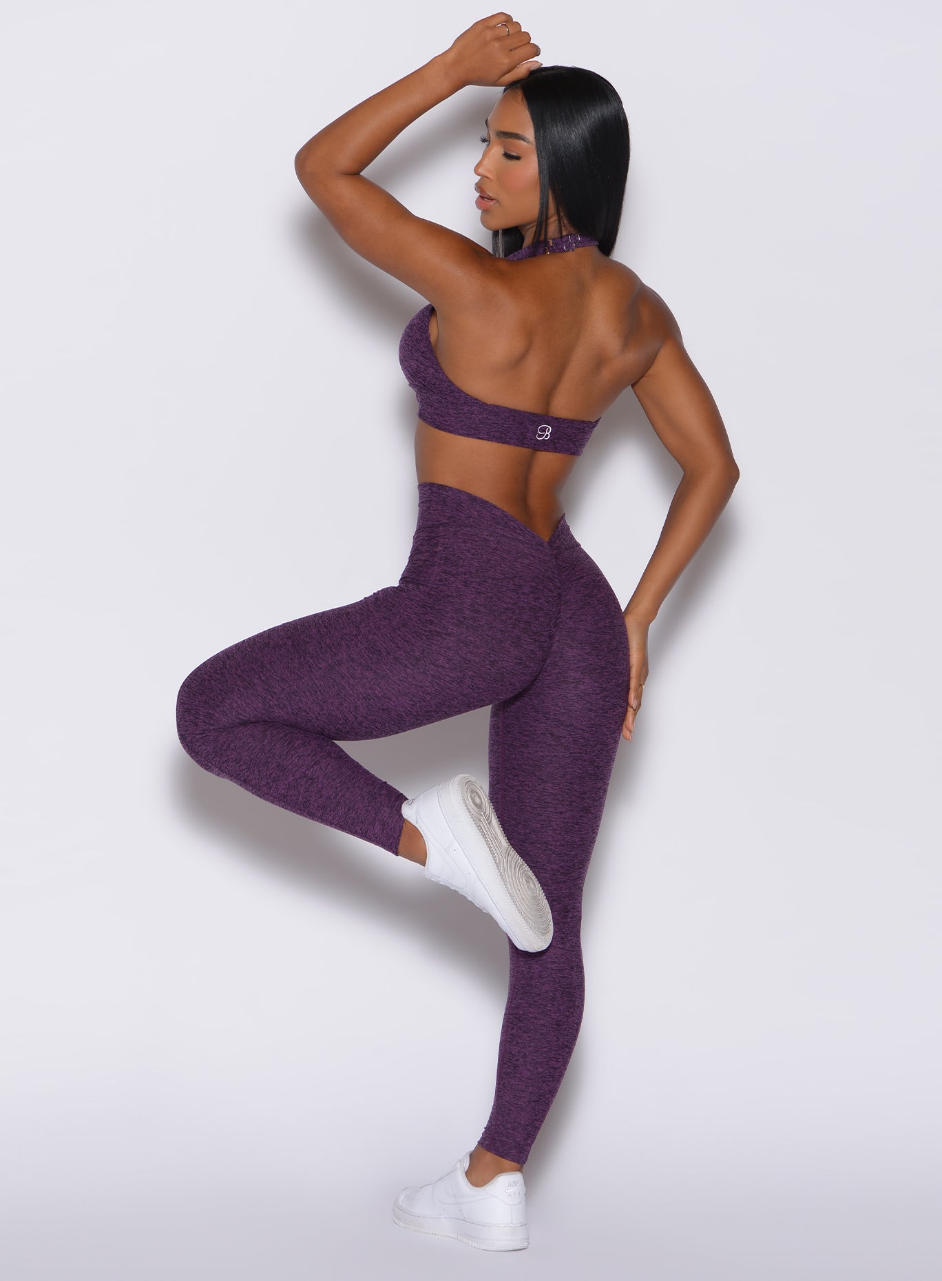 back  profile view of a model in our V Back Leggings in purple passion color along with the matching bra