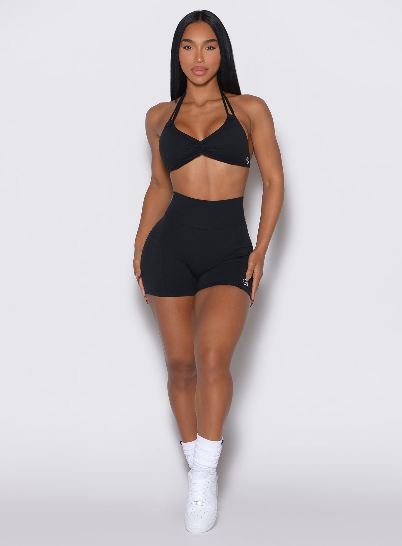front profile view of a model wearing our black V back shorts along with the matching sports bra