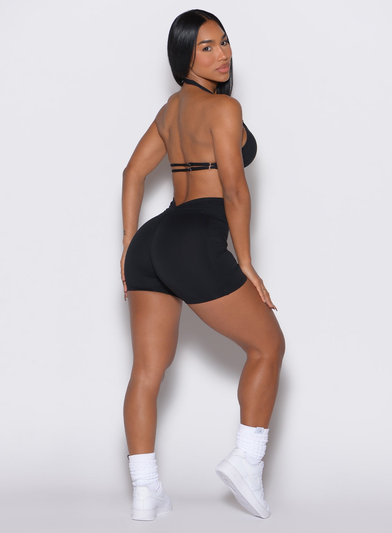 right side profile view of a model wearing our black V back shorts along with the matching sports bra