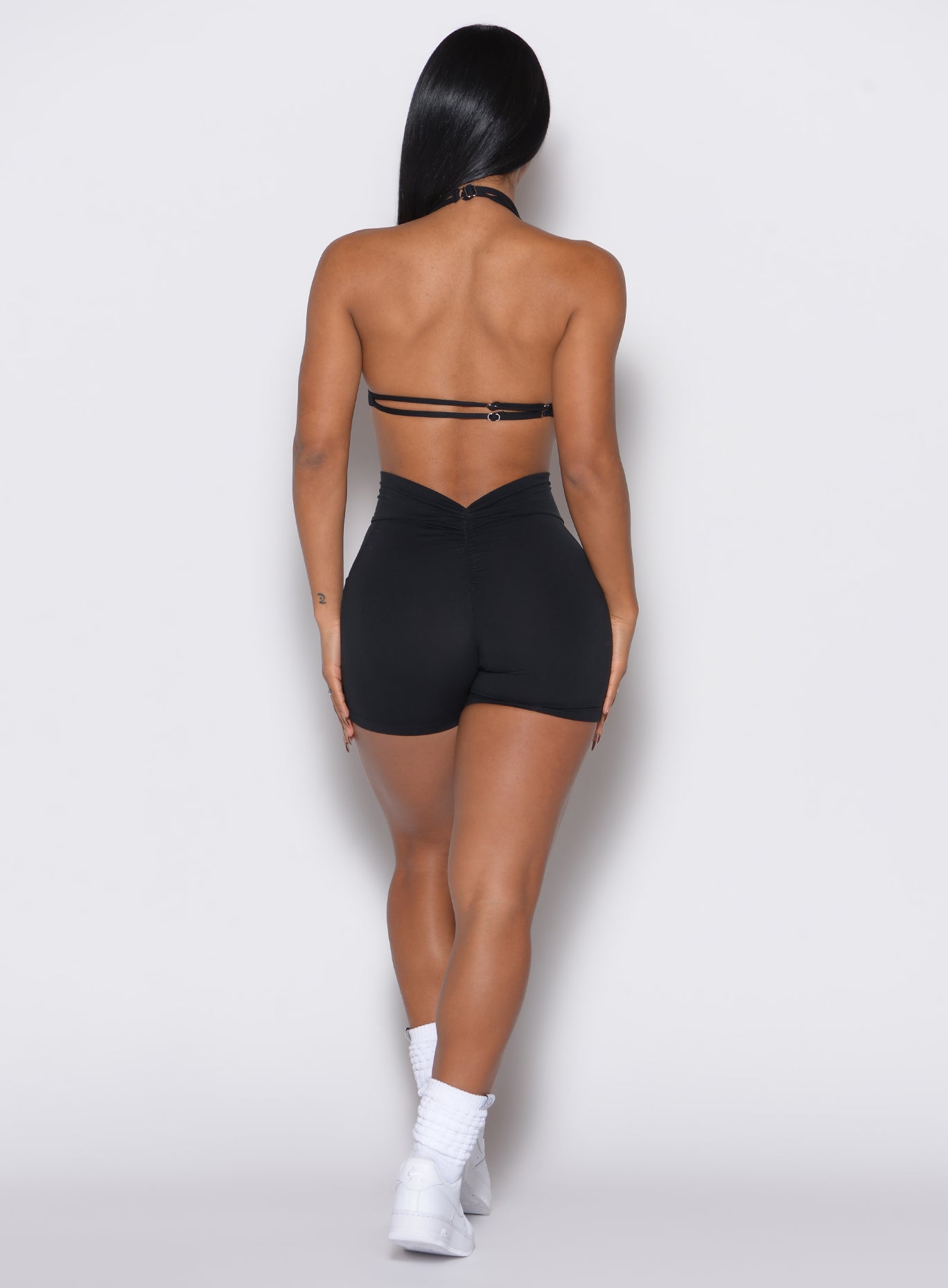 back profile view of a model wearing our black V back shorts along with the matching sports bra