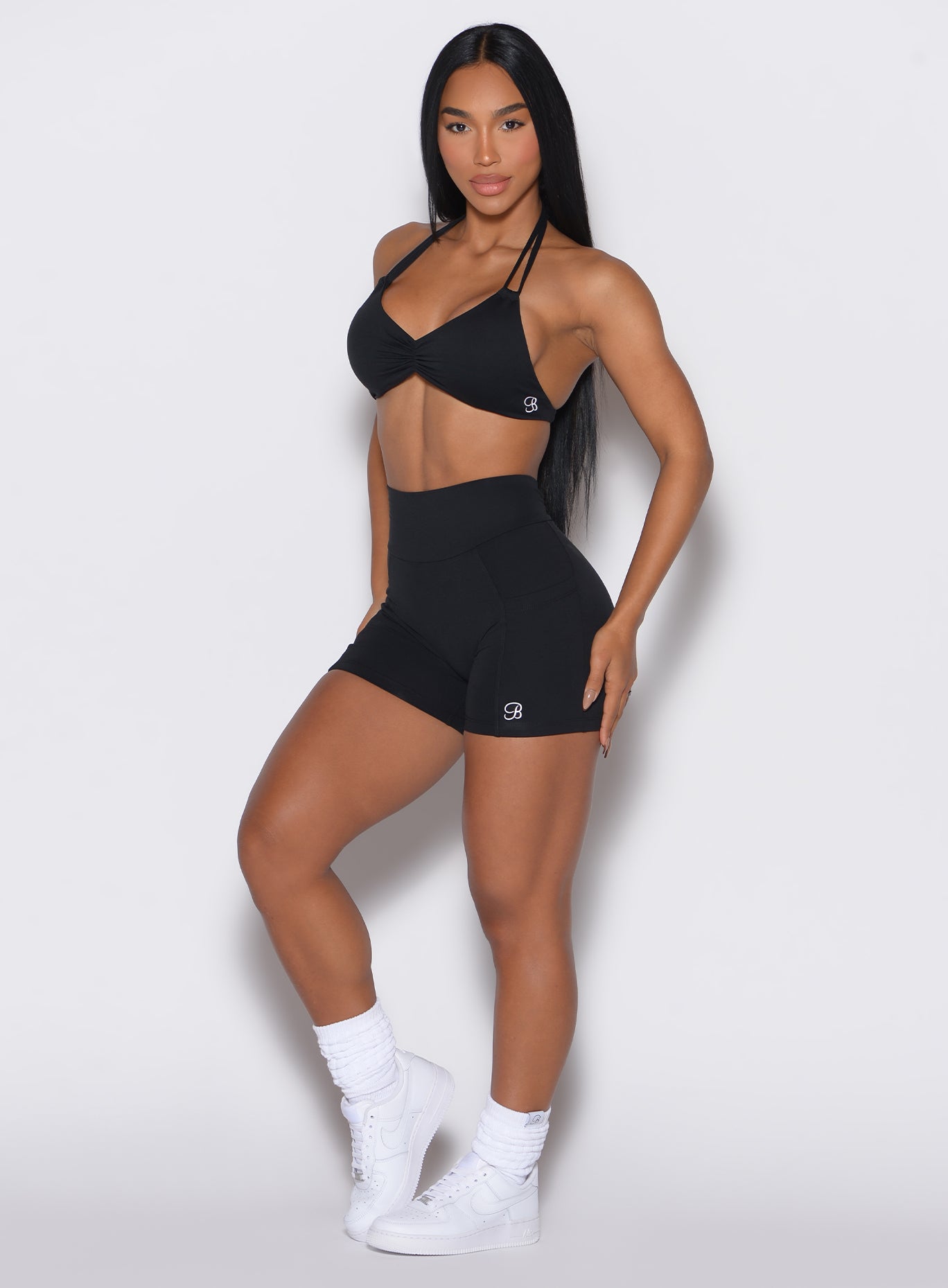 front profile picture of a model wearing our black V back shorts along with the matching sports bra