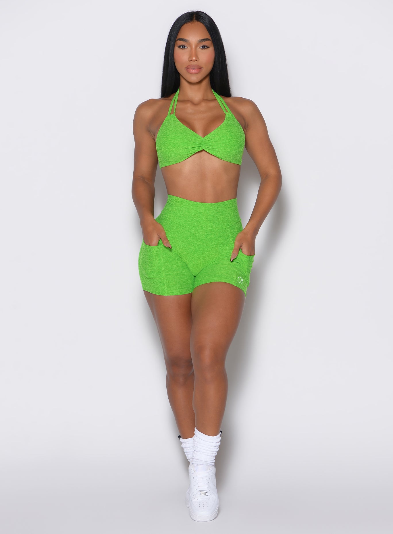 front profile view of a model wearing our V back shorts in Neon Lime Green color along with the matching bra
