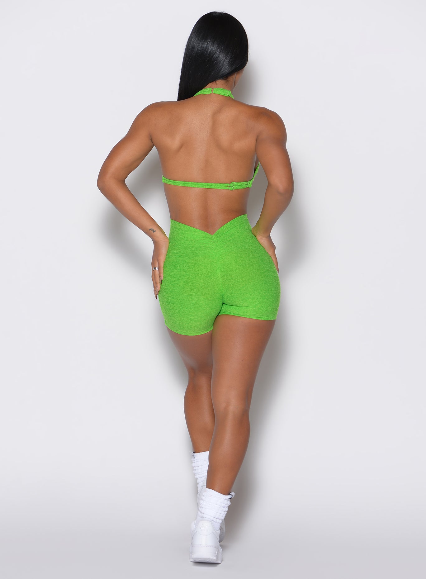 back profile view of a model wearing our V back shorts in Neon Lime Green color along with the matching bra 